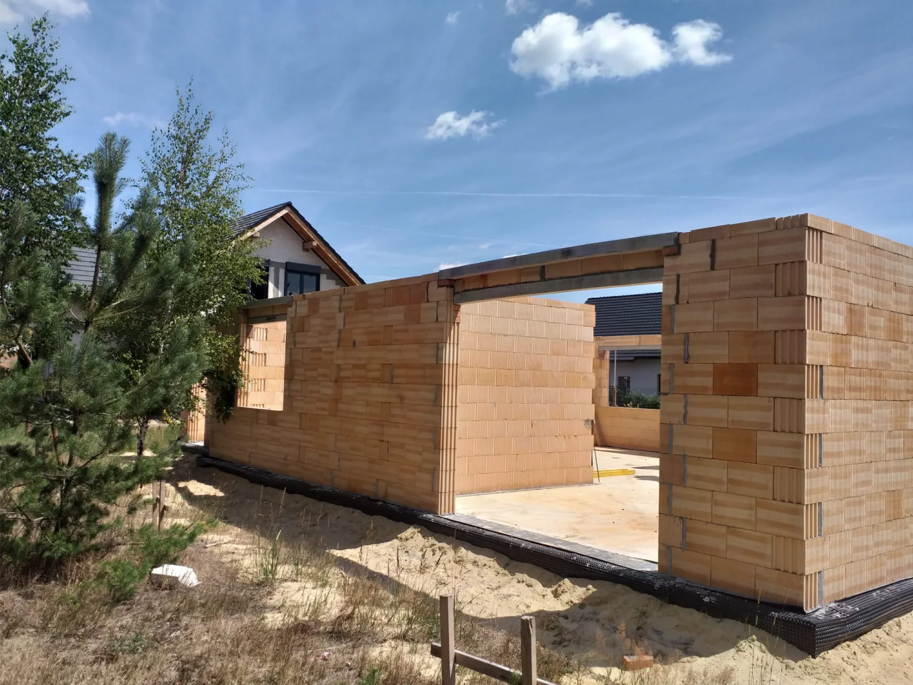 Stan surowy domu: murowane ściany na płycie fundamentowej w trakcie budowy