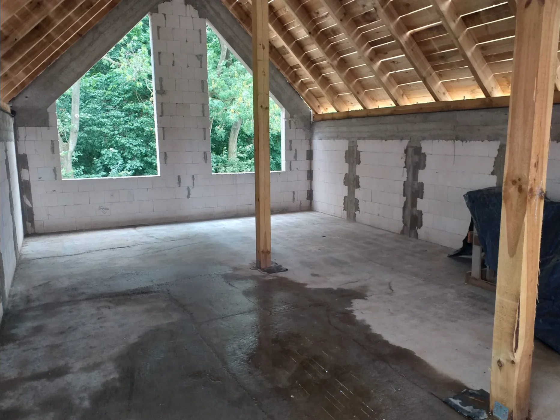 Nieotynkowane ściany z bloczków i widoczna więźba dachowa w trakcie adaptacji poddasza