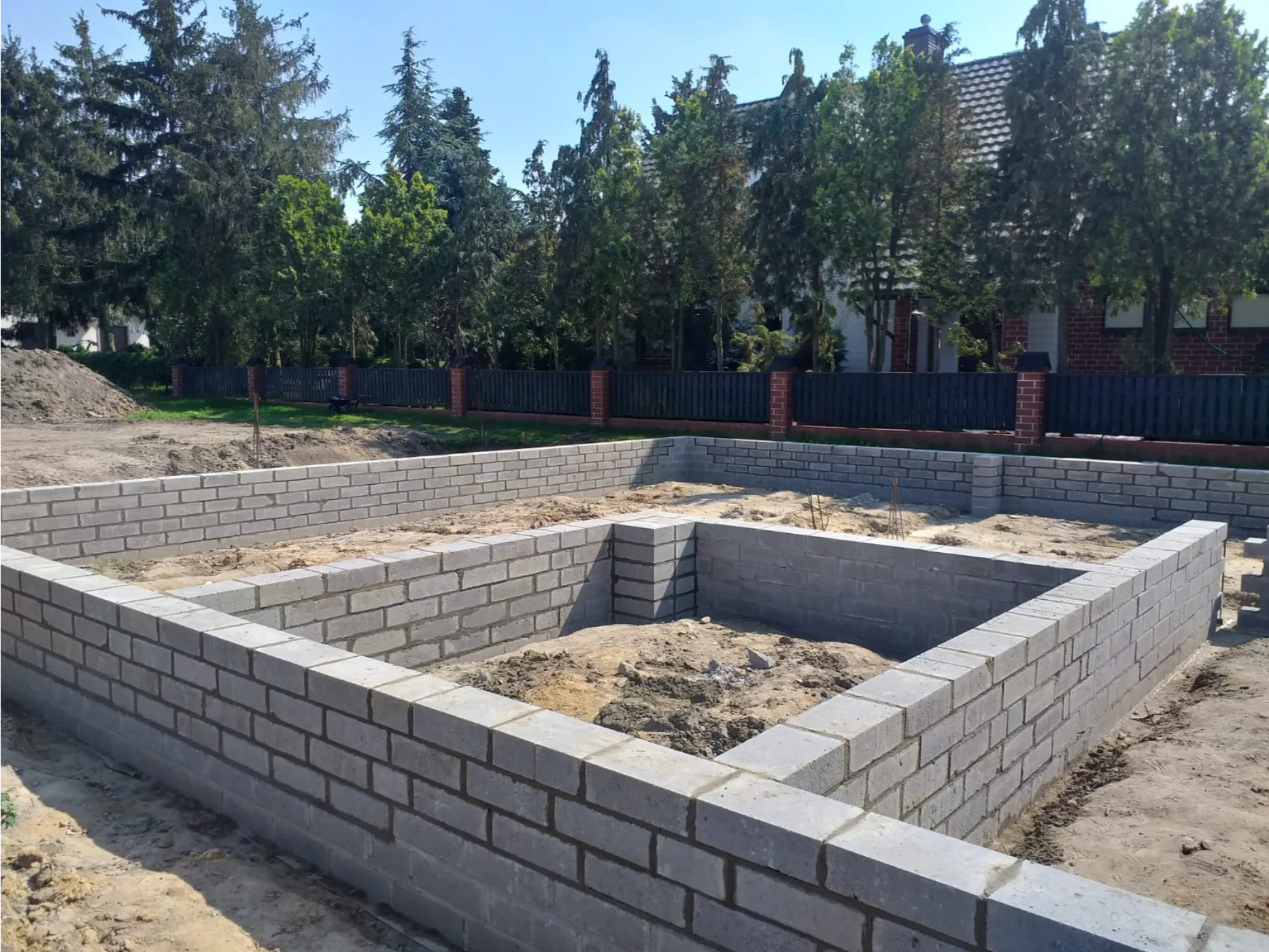 Widok fundamentu wykonany z betonowych bloczków w wykopie – przygotowanie płyty fundamentowej pod dom
