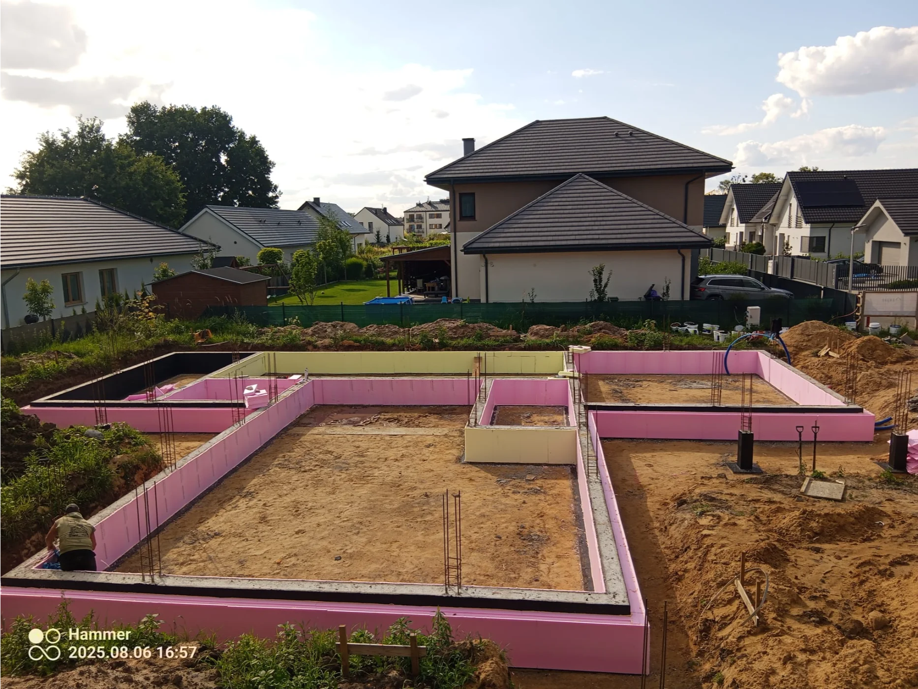 Płyta fundamentowa z różowymi styropianowymi deskami i wystającą zbrojeniówką na budowie domu