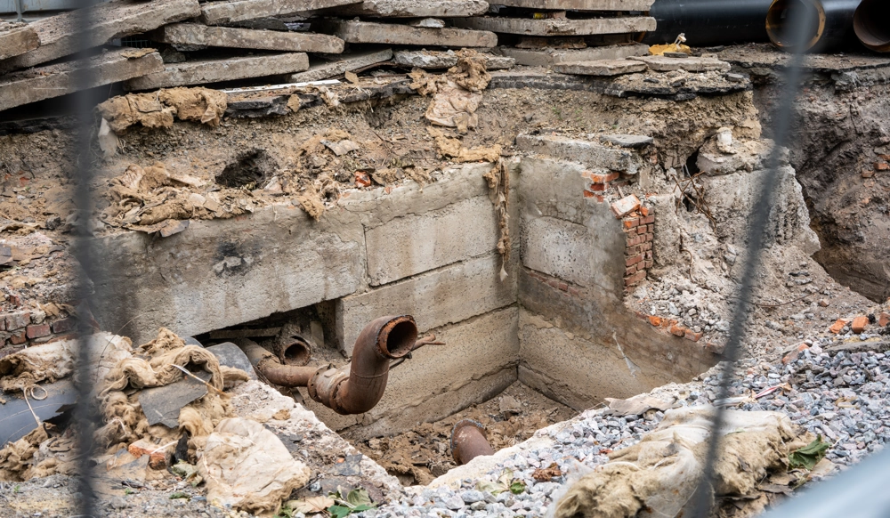 Wykop pod kanalizację z betonowymi fundamentami i widocznymi rurami ściekowymi