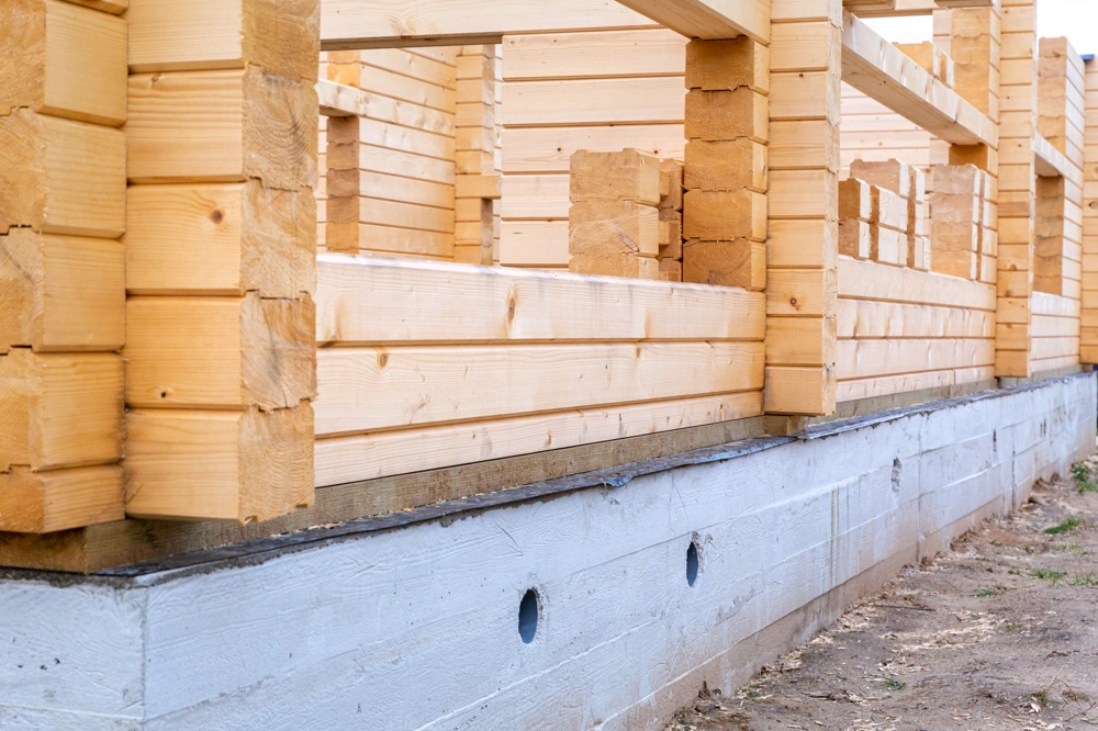 Stan surowy domu: montaż drewnianych ścian na betonowej płycie fundamentowej